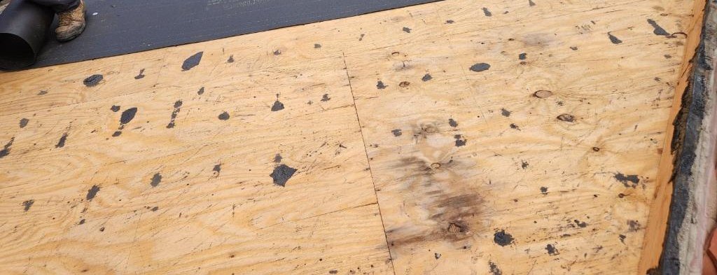 Plywood roof decking beside a sheet of underlayment