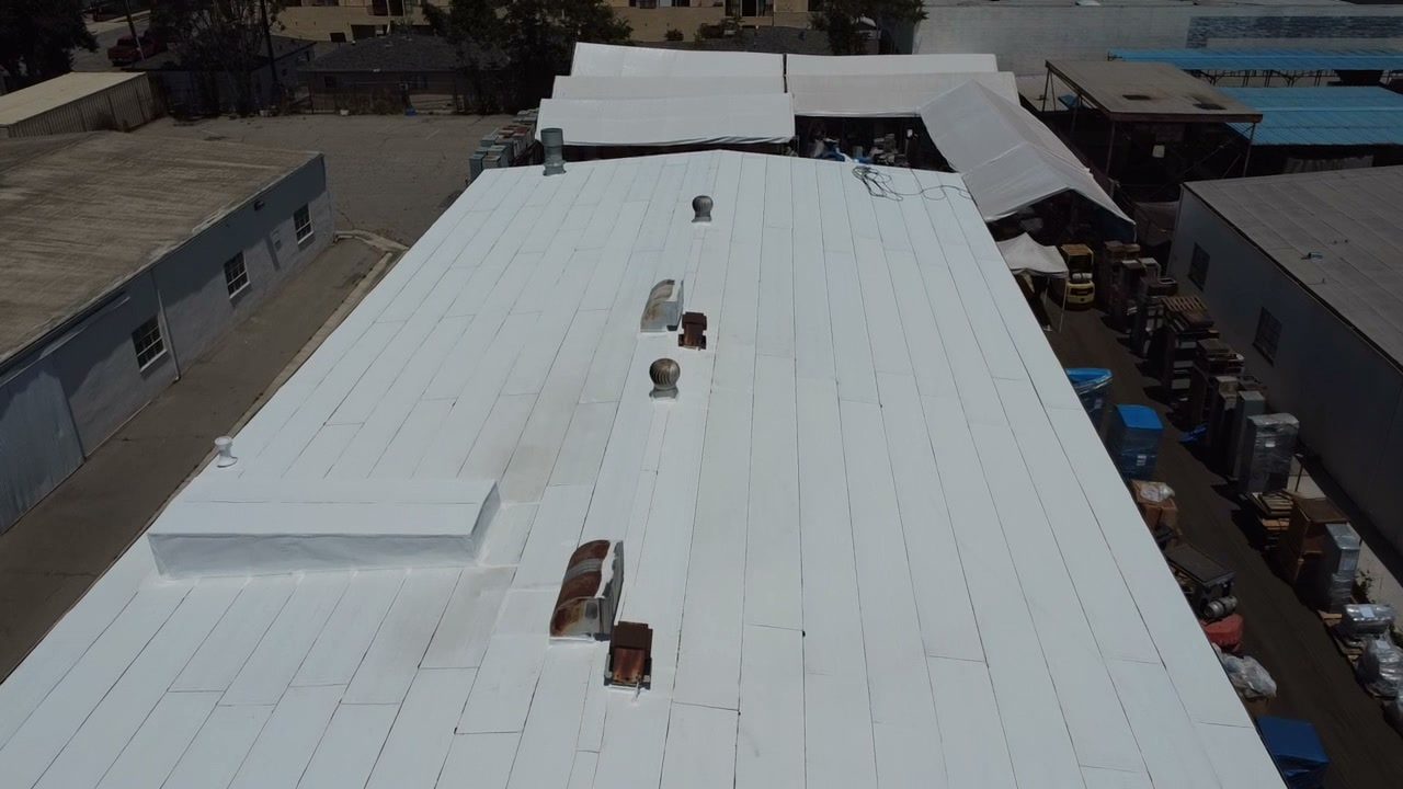 Long low-slope roof with repeated vents beside a service yard