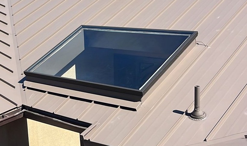 Standing-seam metal panels around a skylight and pipe flashing