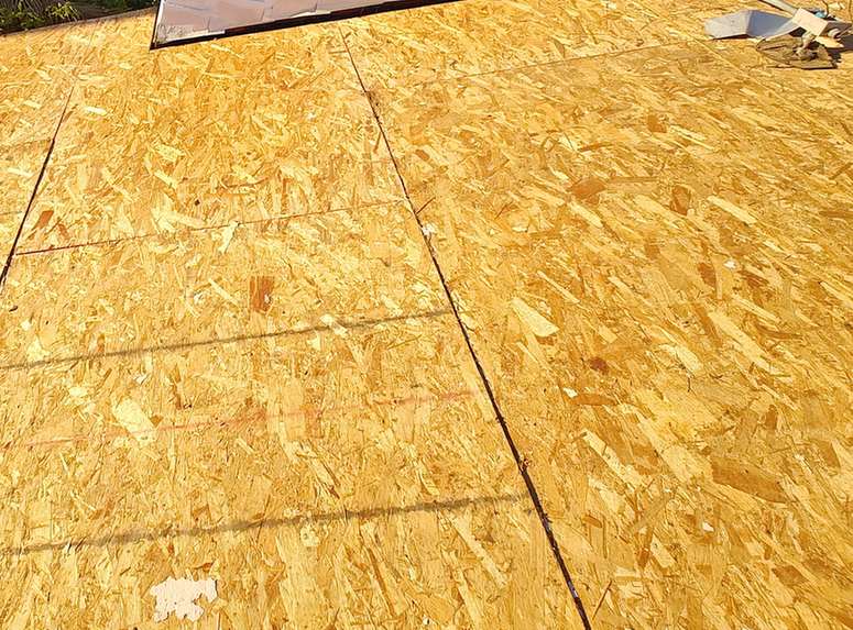 Exposed OSB roof decking at a brick chimney