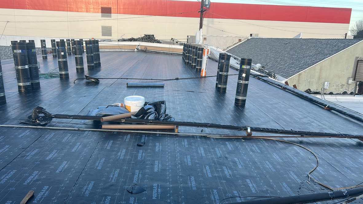 Packaged roofing rolls and tools on black base sheets