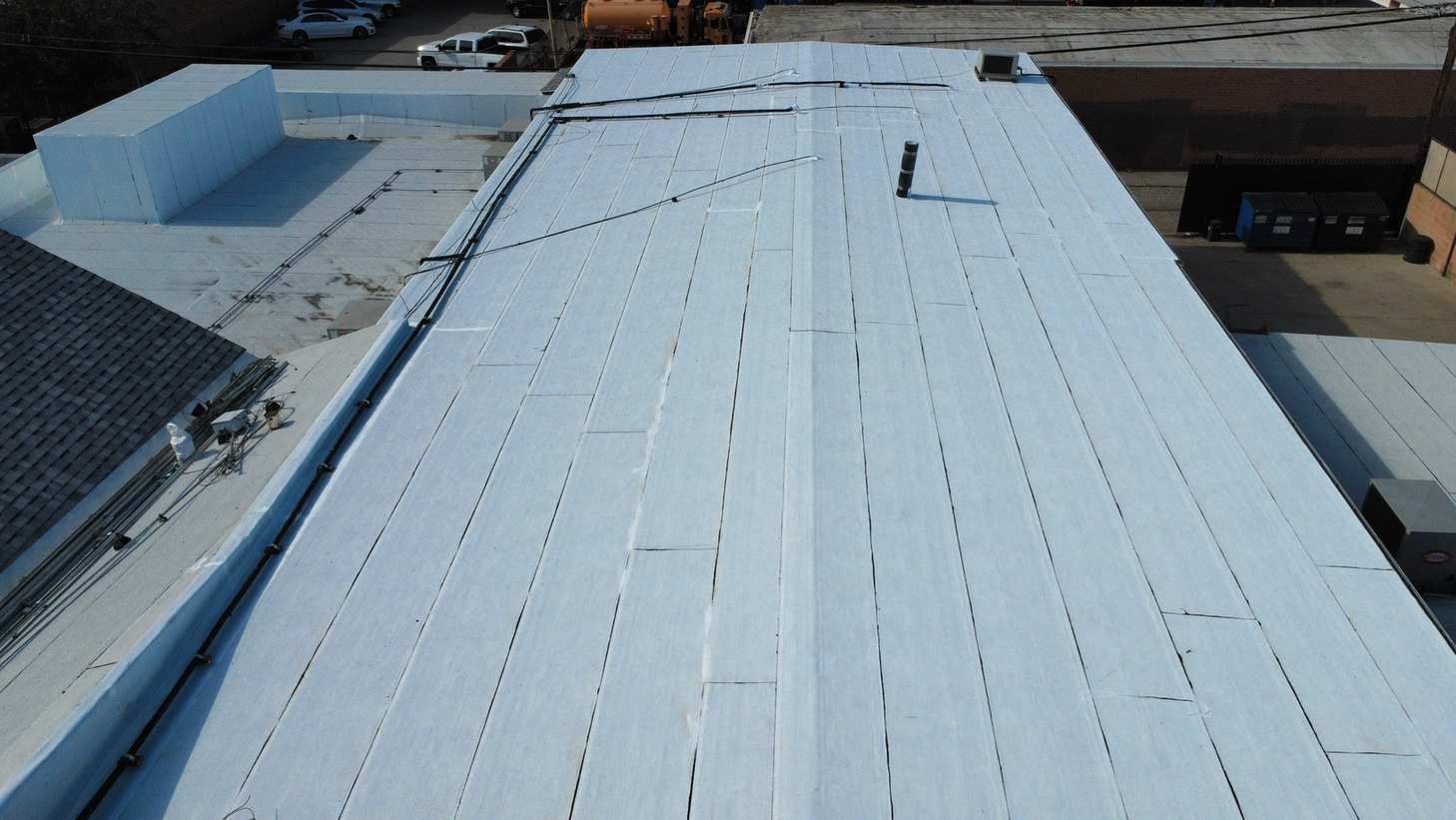 Low-slope roof with sheet overlaps, pipes and a raised enclosure